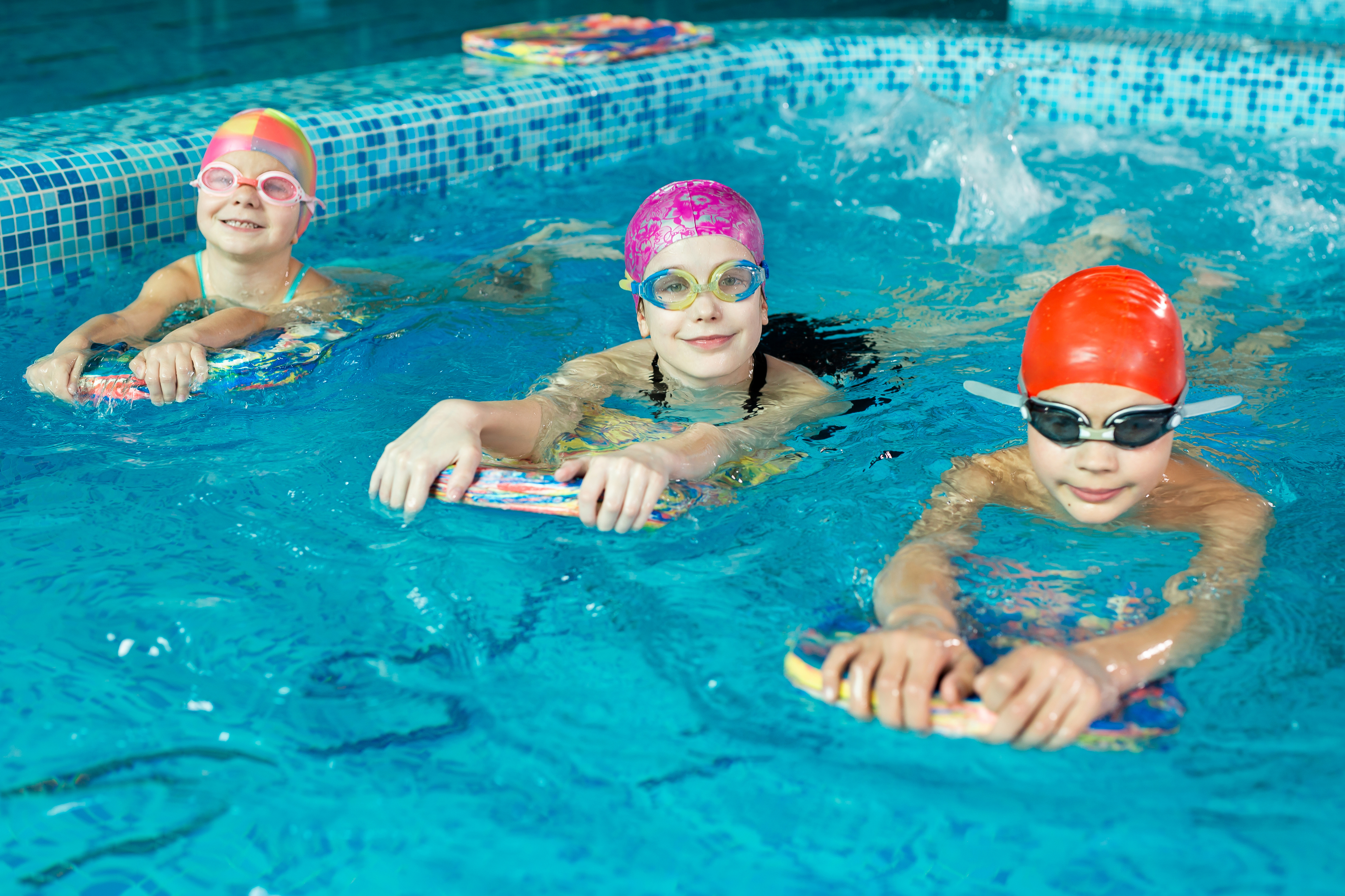 Drei Kinder schwimmen mit Schwimmbretter